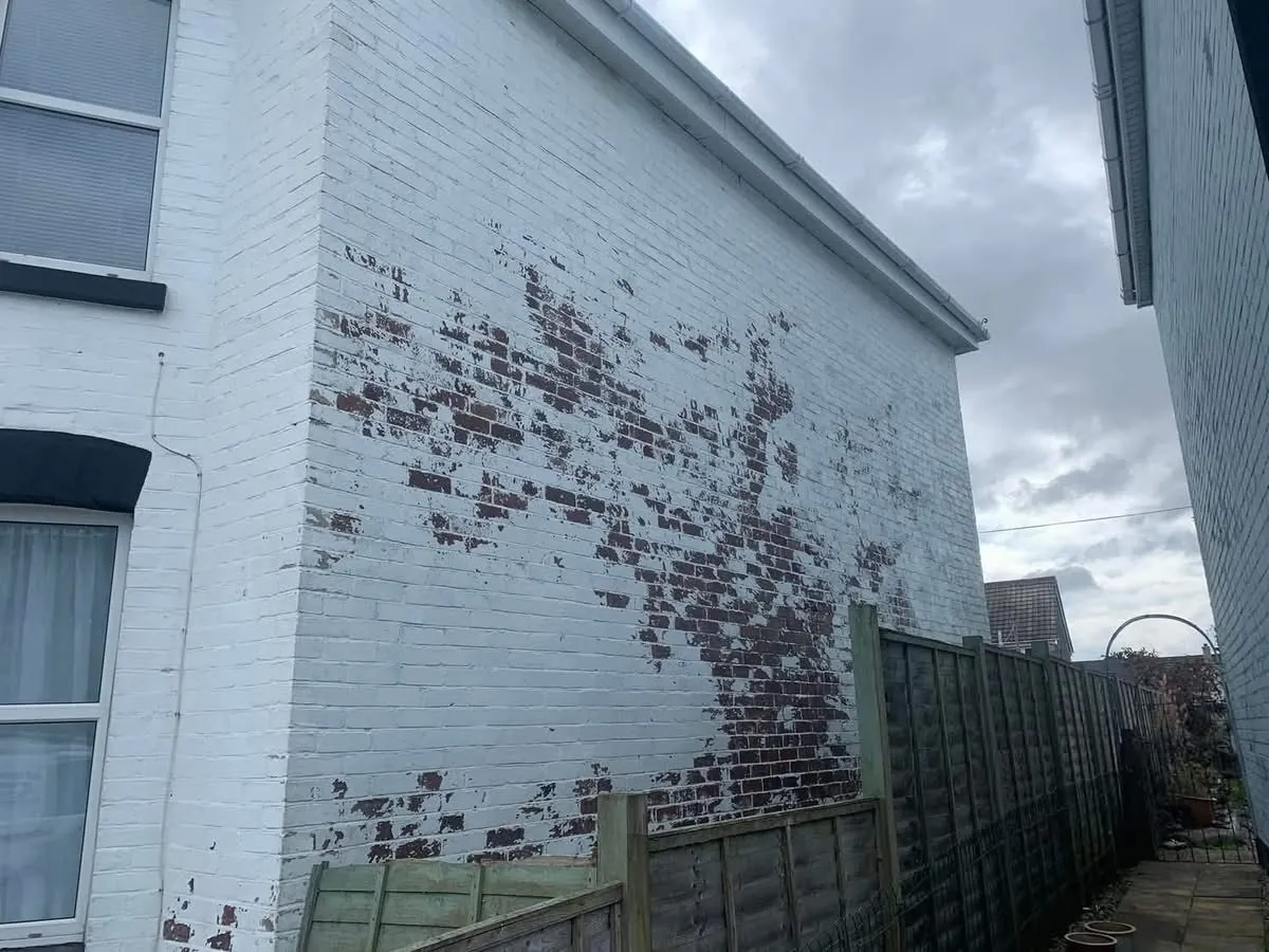 Peeling paint on a brick wall before redecoration in Redruth